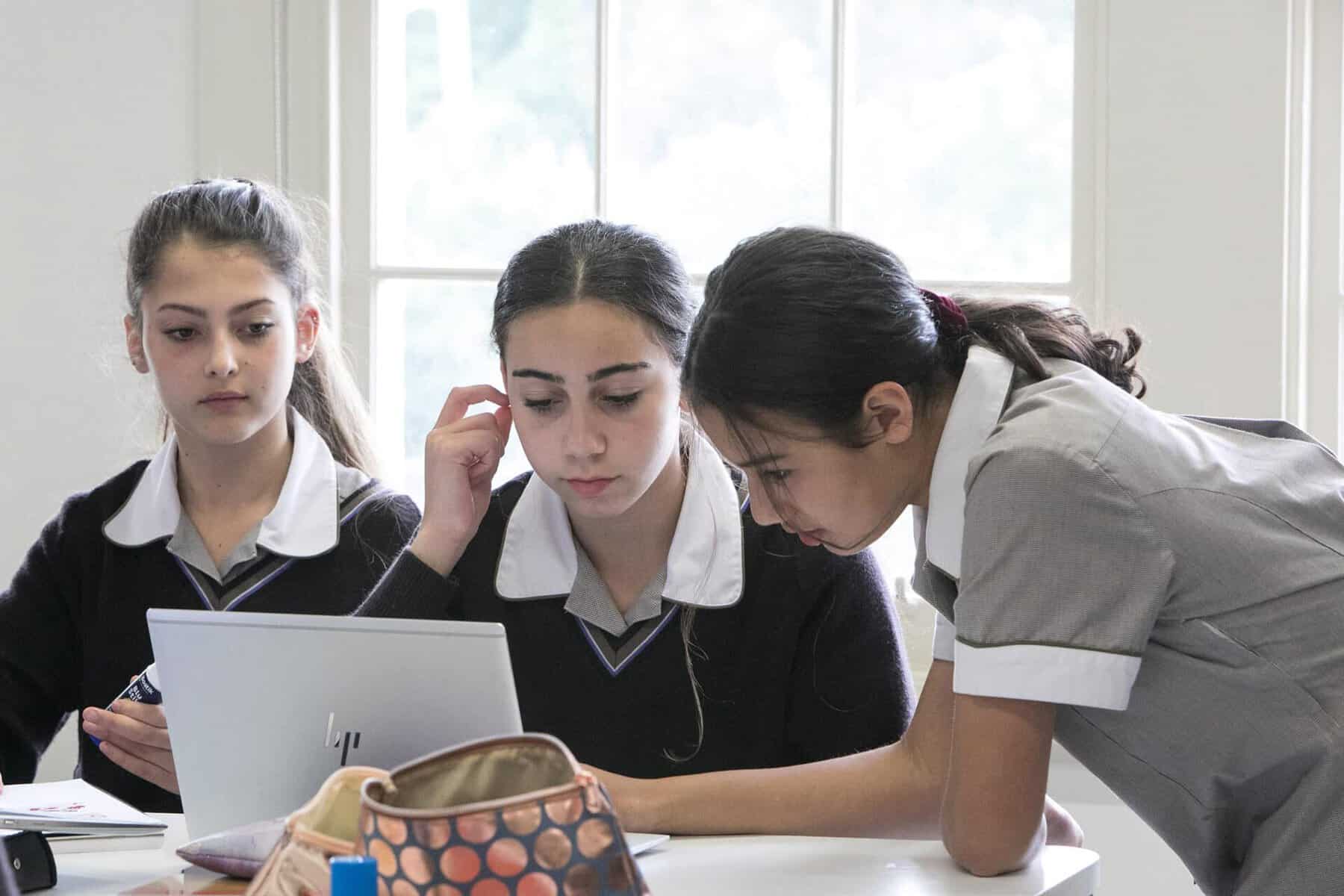Students collaborating on a laptop in a classroom at Ivanhoe Grammar School.