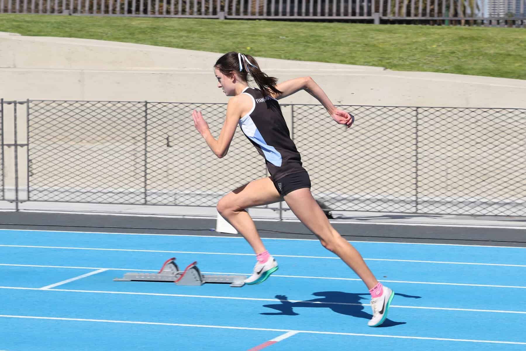 Young female athlete sprinting on a blue running track at Ivanhoe Grammar School.