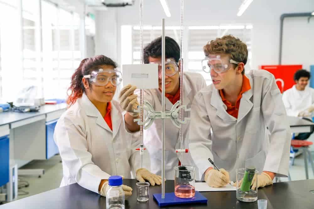 Students conducting a science experiment in a modern laboratory at Raffles American School.