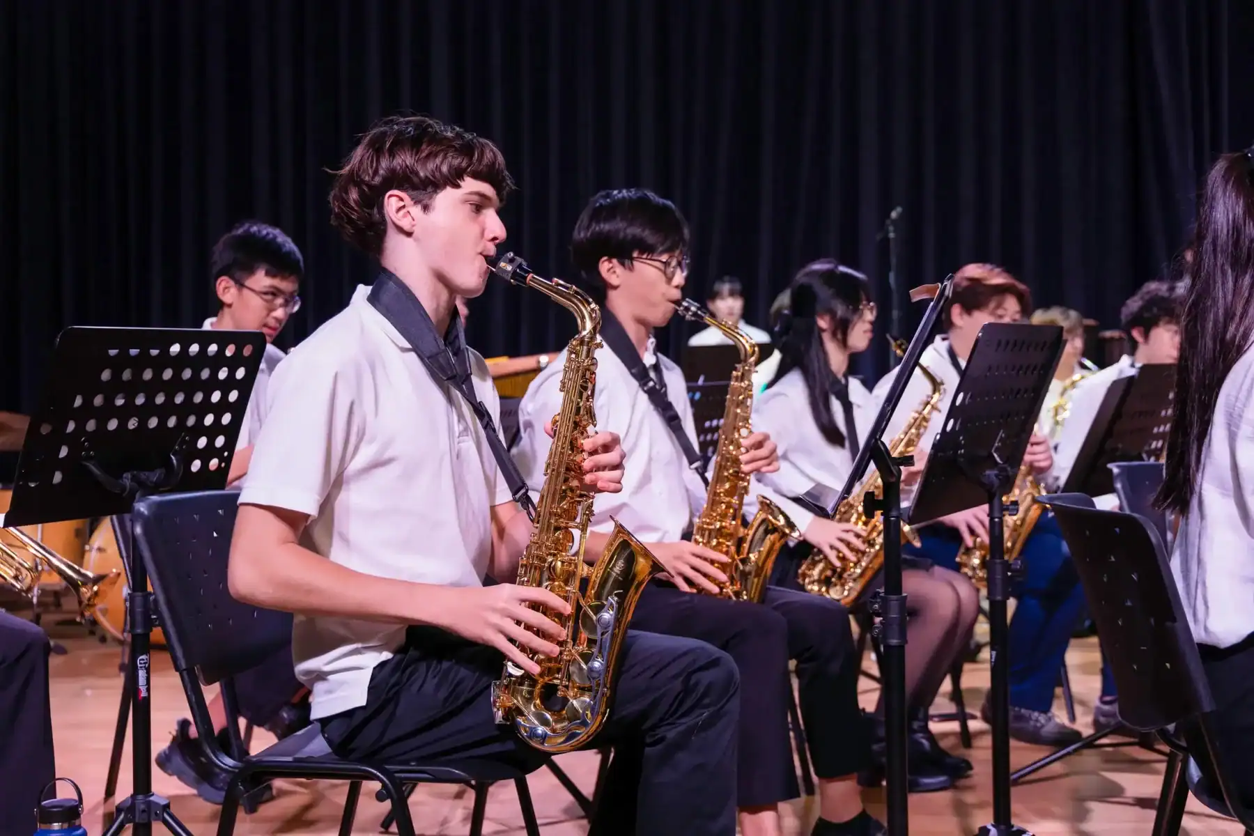 Students playing saxophones in a school band performance.