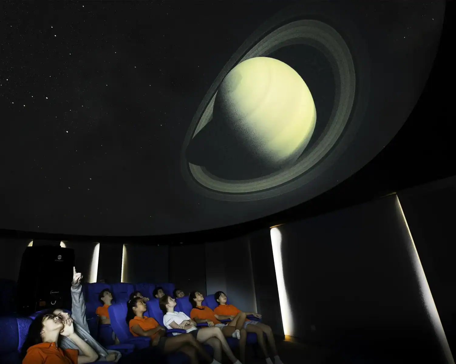Children watching a planetarium show about Saturn and its rings.