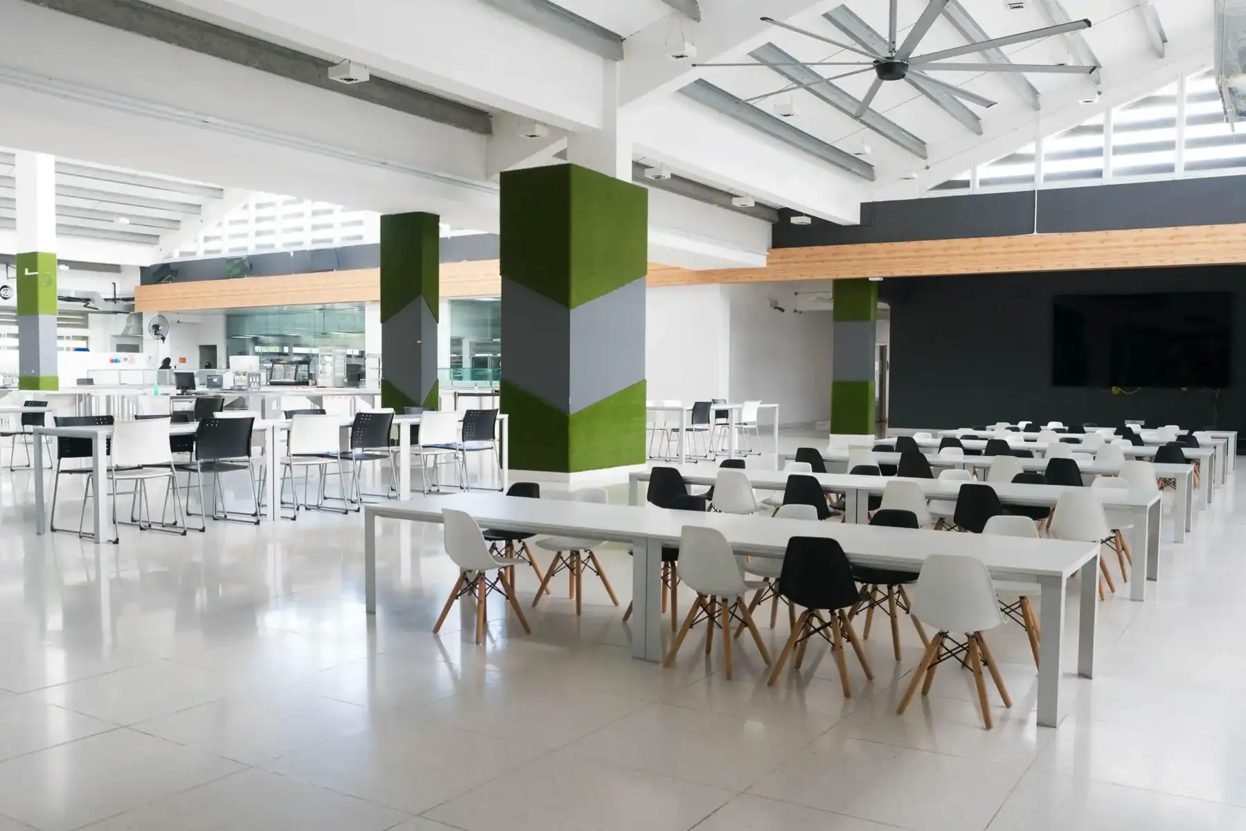 Modern school cafeteria with white tables and black and white chairs.