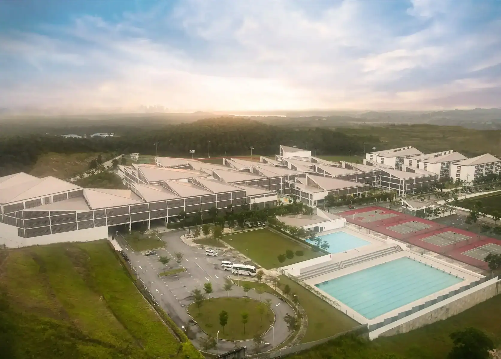 Aerial view of Raffles American School with pools and sports facilities.