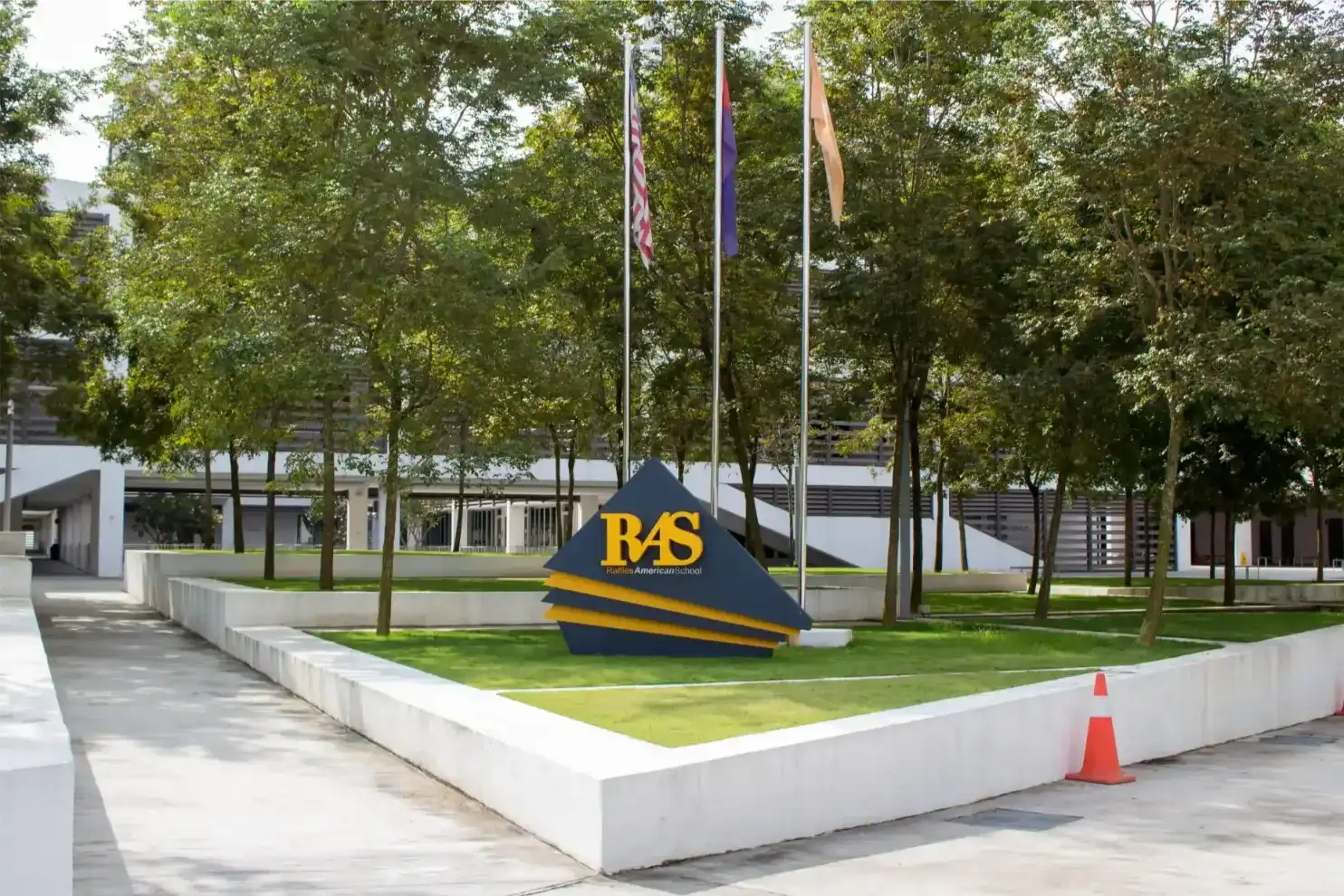 Raffles American School entrance with flags and modern architecture.