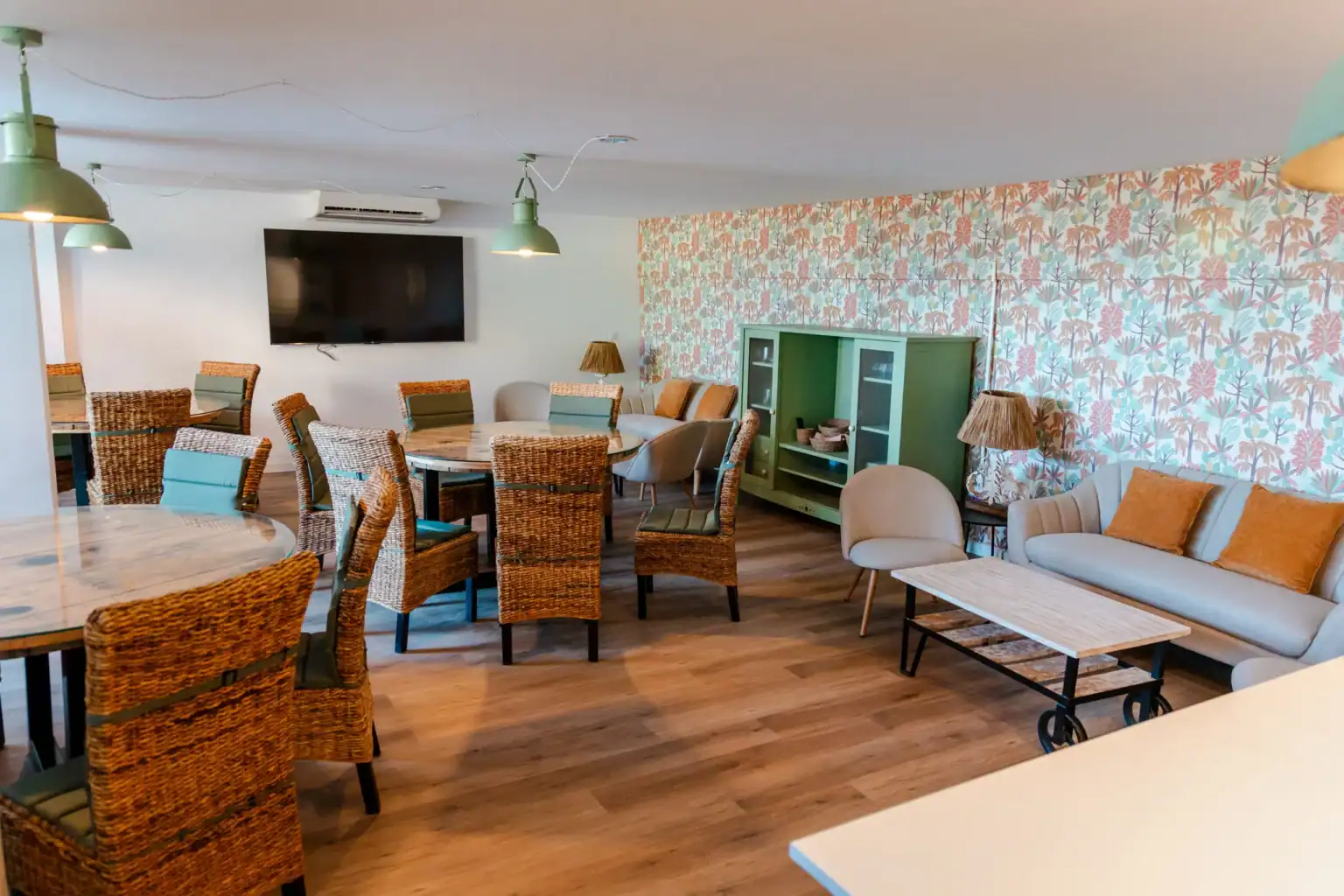 Cozy classroom lounge with wicker chairs, sofas, and vibrant wallpaper for comfortable student relaxation.