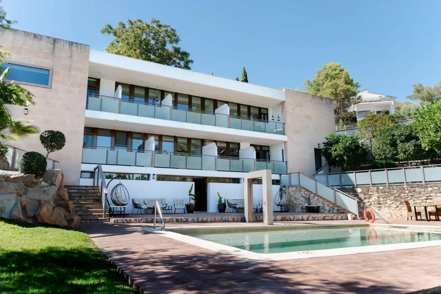 Modern luxury school building with pool and outdoor lounge area, ideal for international students.