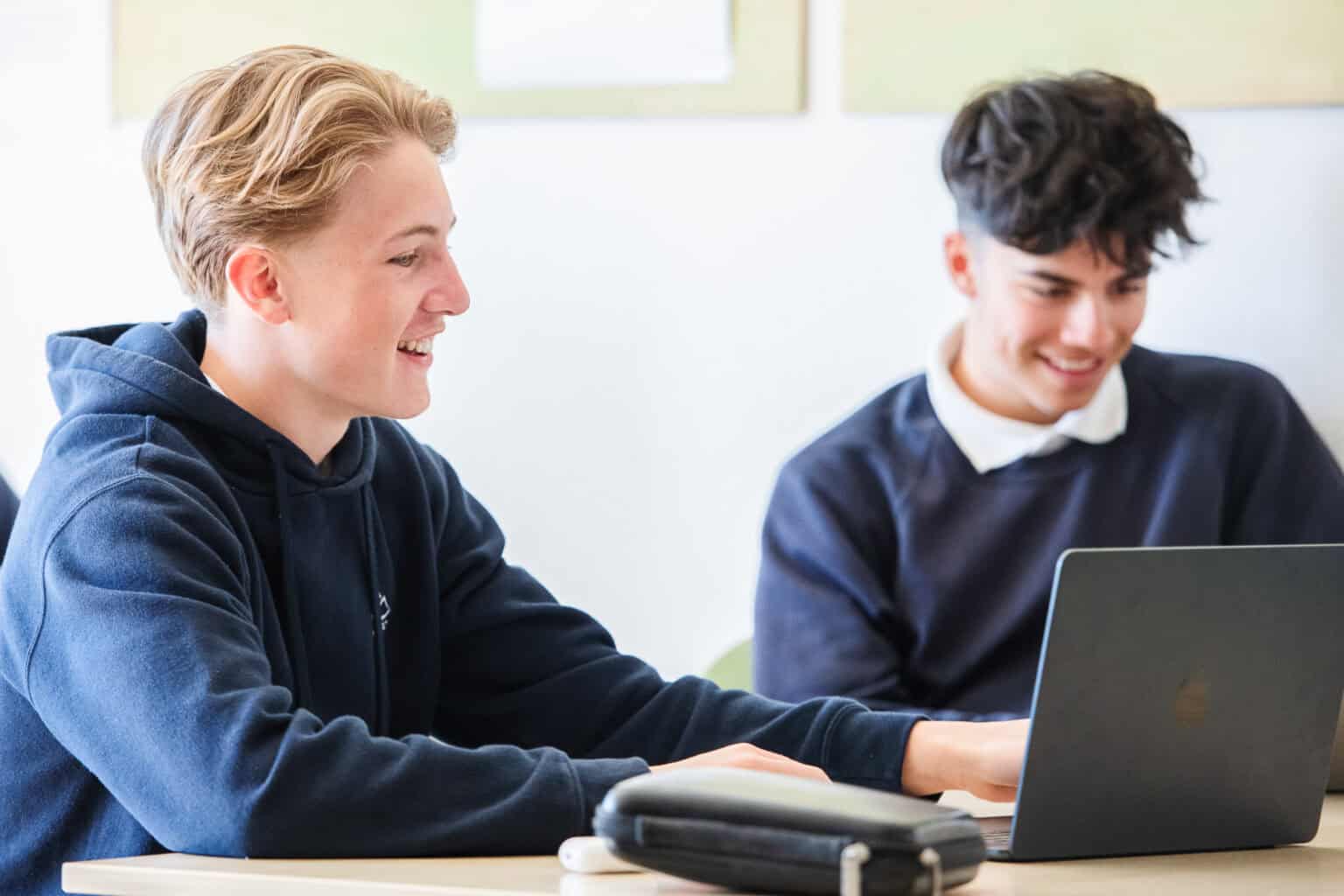 Engaged students collaborating on a laptop in a modern school setting, emphasizing world schools and educational excellence.