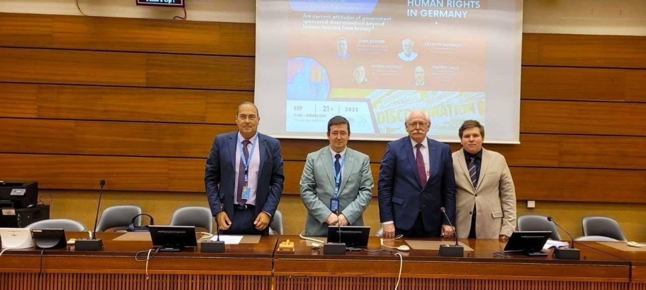 Four men standing at a conference table during a human rights event.