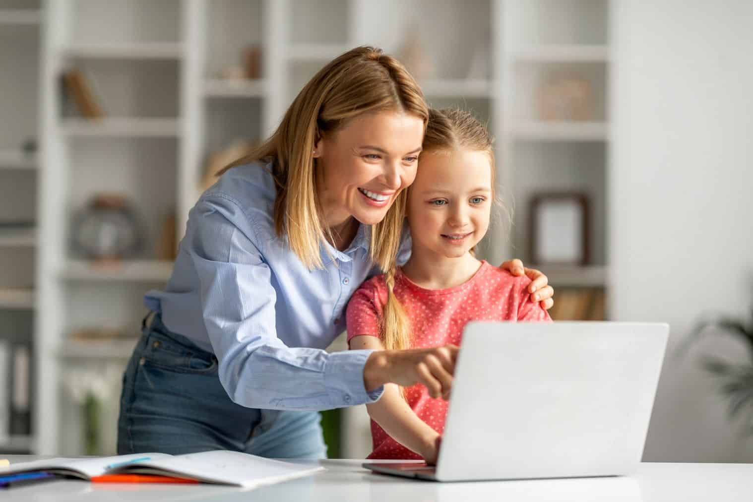 Teacher and young girl using laptop for learning at home.