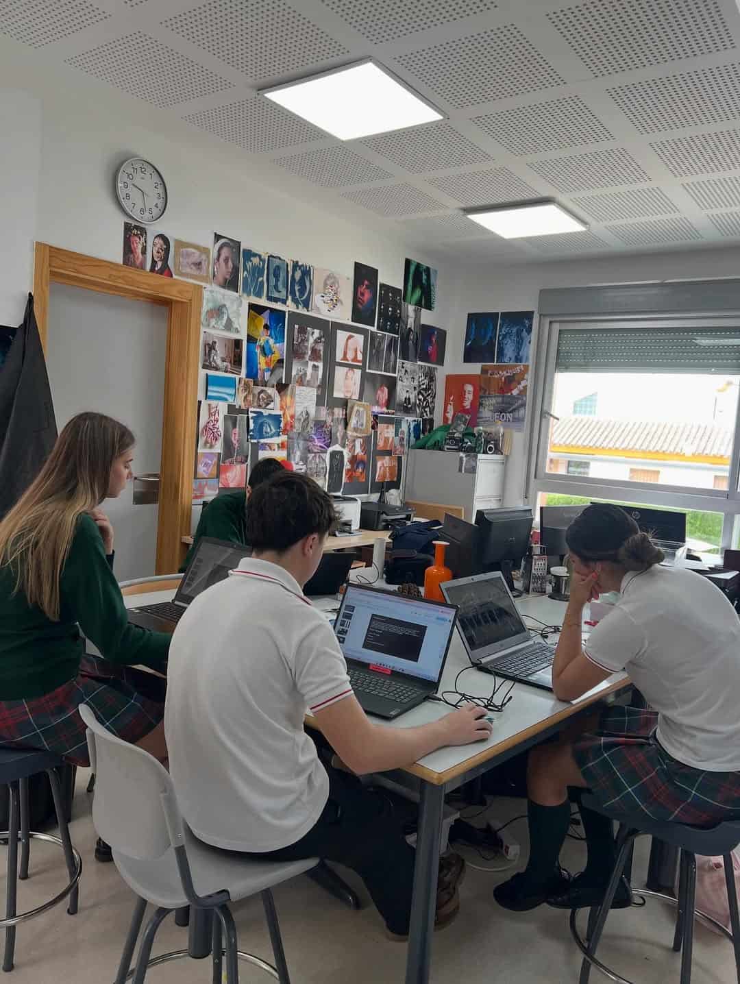 Modern classroom with students using laptops and digital devices.