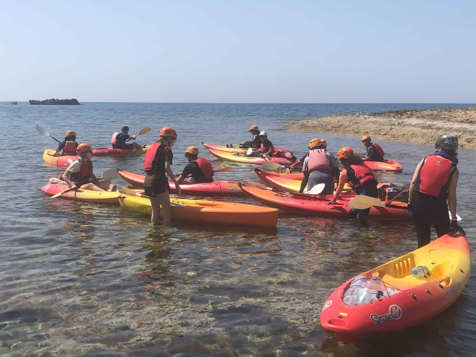 Kids kayaking at a seaside educational retreat, outdoor adventure activity for students at global schools.