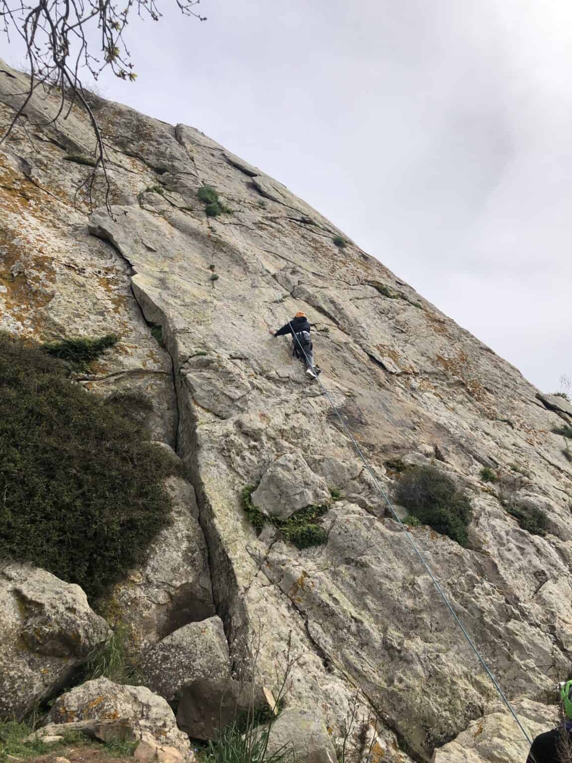 Climber ascending a steep outdoor rock face, demonstrating adventure and extreme sports.