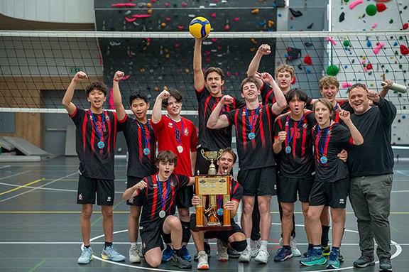 A Season of Growth, Grit, and Championship Spirit in LAS Volleyball 8 Young volleyball team celebrating victory with medals and trophy at indoor sports facility.