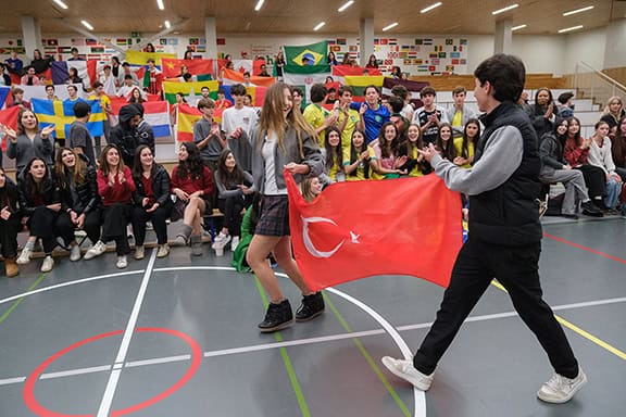 Students celebrating multicultural diversity at World Schools event with flags from around the world.