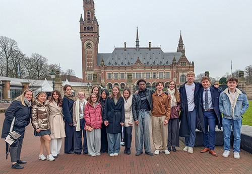 Diverse group of students standing together in front of a historic castle-like structure, representi.