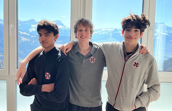 Group of three students at World Schools with mountain scenery behind.