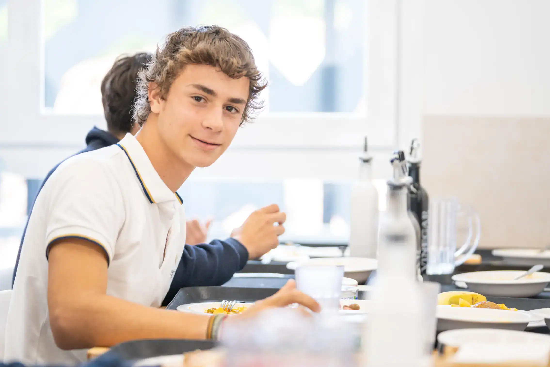 Bystry uczeń spożywający posiłek w stołówce szkolnej na całym świecie, promujący zdrowe odżywianie uczniów.