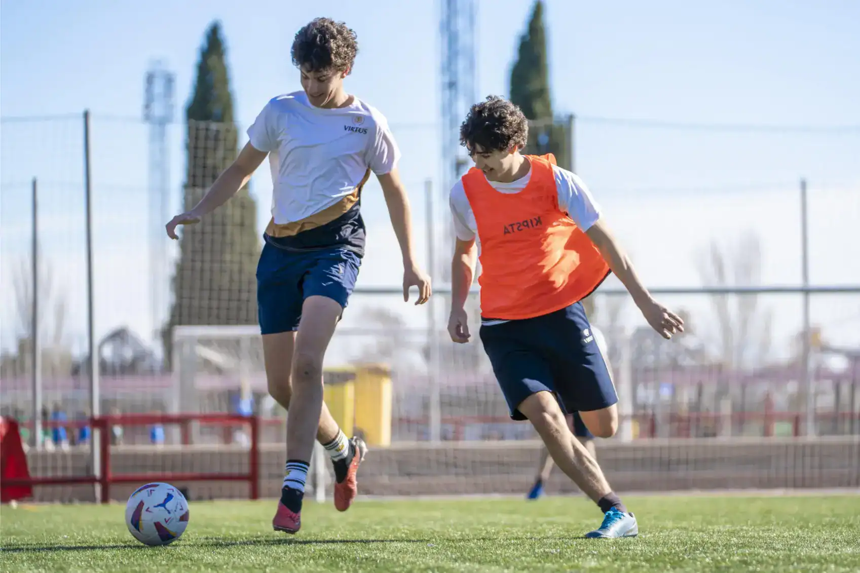 Aktywni chłopcy grający w piłkę nożną na szkolnym boisku sportowym podczas zajęć wychowania fizycznego w World Schools.