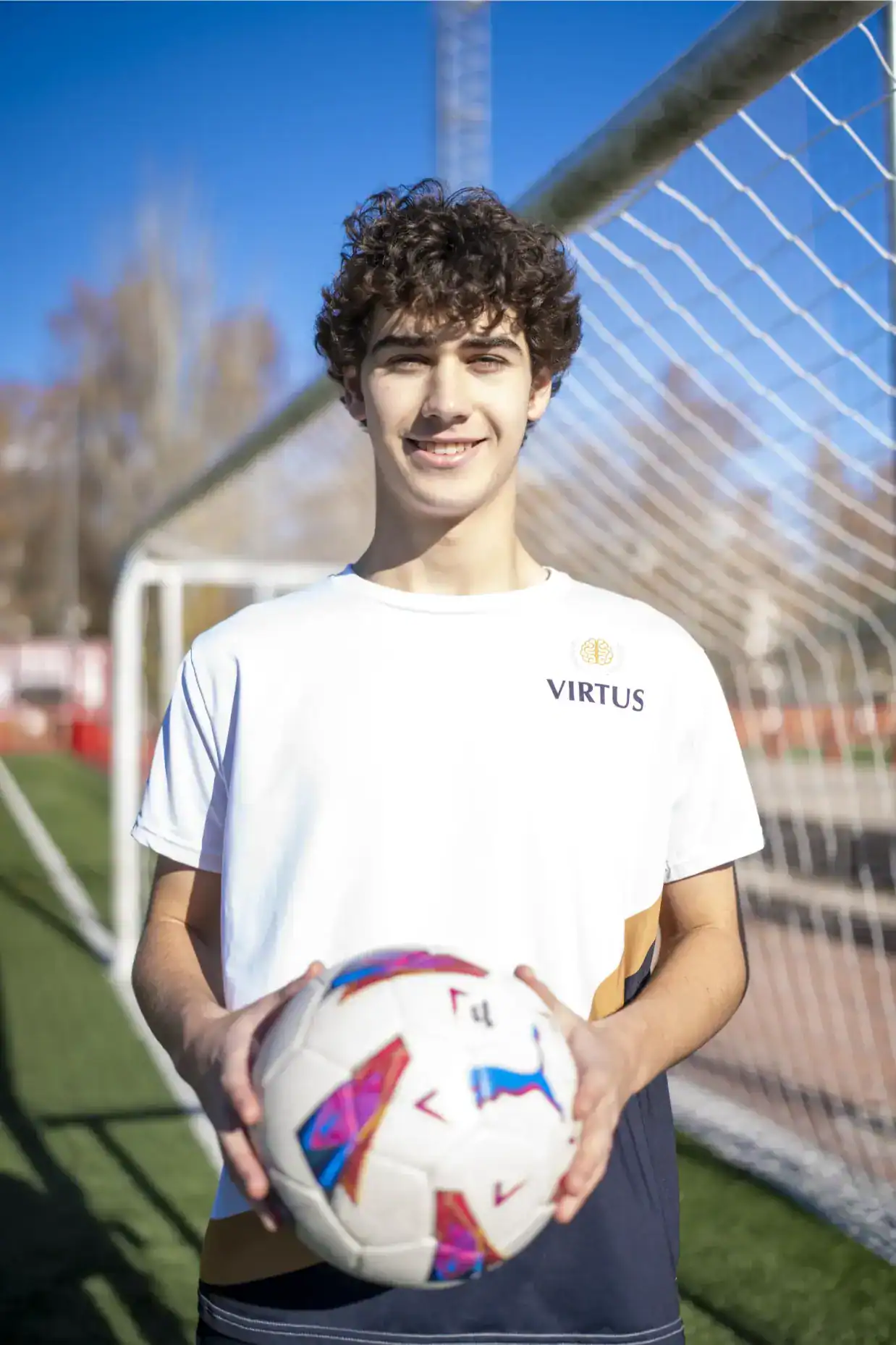 Aktywny uczeń z piłką na boisku sportowym w ramach programu World Schools.