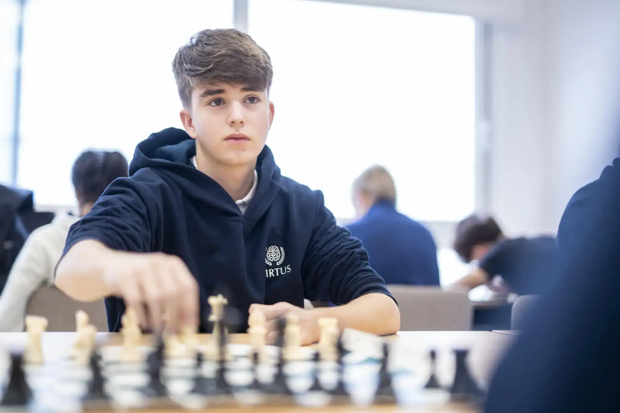 Skupiony nastolatek grający w szachy w międzynarodowej szkole, prezentujący doskonałość akademicką i strategiczne myślenie w środowisku edukacyjnym.