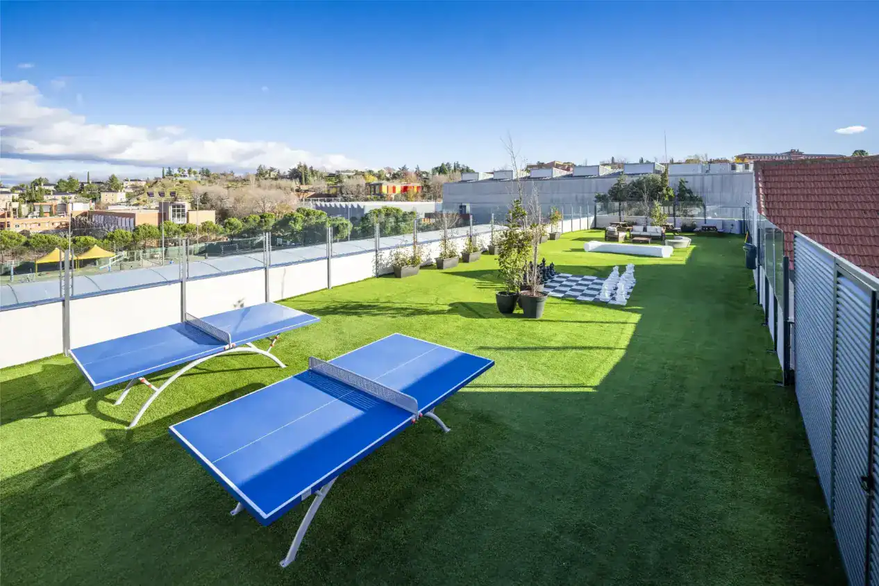 Zewnętrzna strefa sportowo-rekreacyjna na dachu w World Schools, idealna do zajęć dla studentów i relaksu.