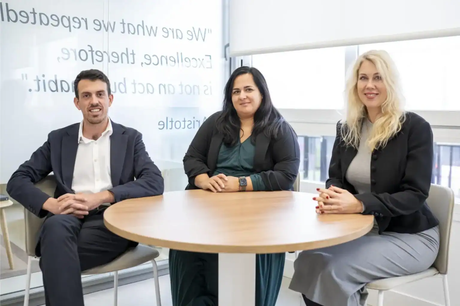 Różnorodni profesjonaliści siedzący przy okrągłym stole w nowoczesnym biurze, promujący globalną edukację i międzynarodową współpracę szkół.