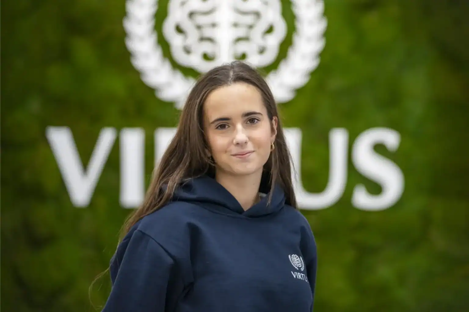 Międzynarodowy student w prestiżowej światowej szkole przed logo uniwersytetu, reprezentujący globalną doskonałość edukacji.