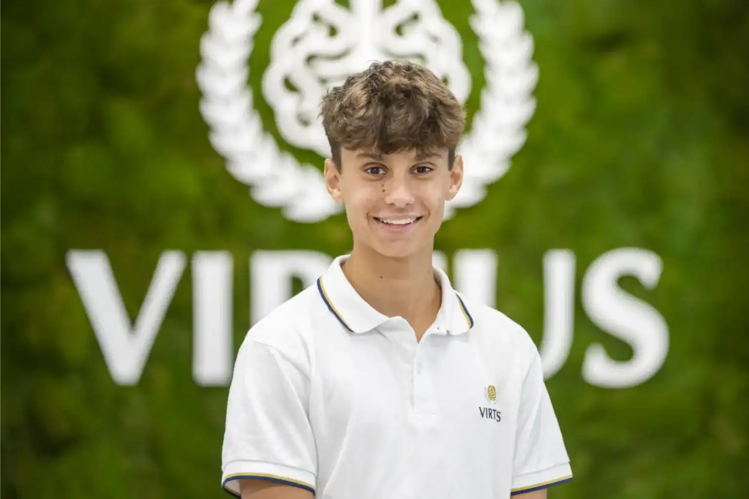 Jasny młody uczeń w World Schools na tle żywego zielonego tła z logo szkoły.