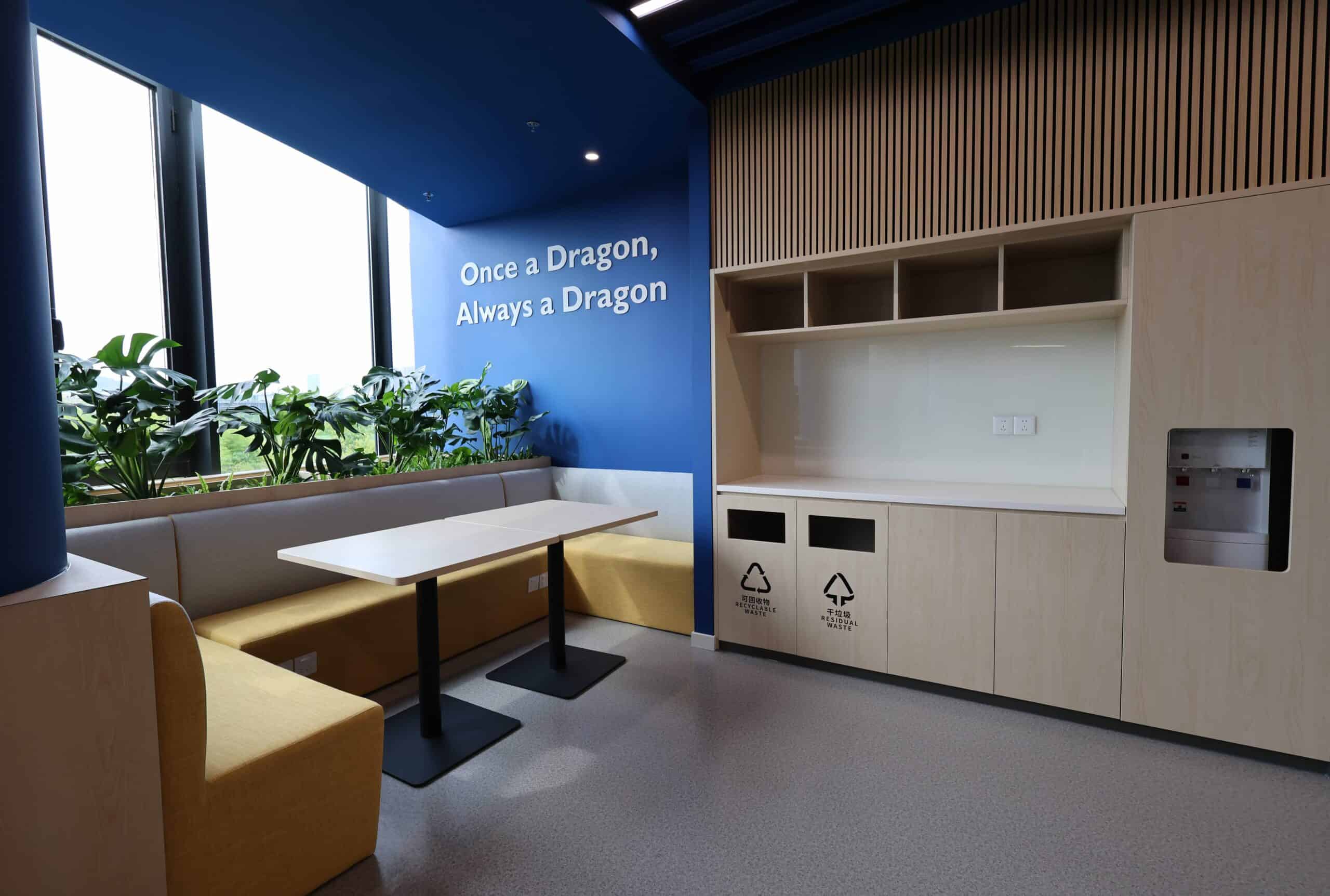 Bright modern school lounge area with plants and motivational quote, ideal for student relaxation and study.