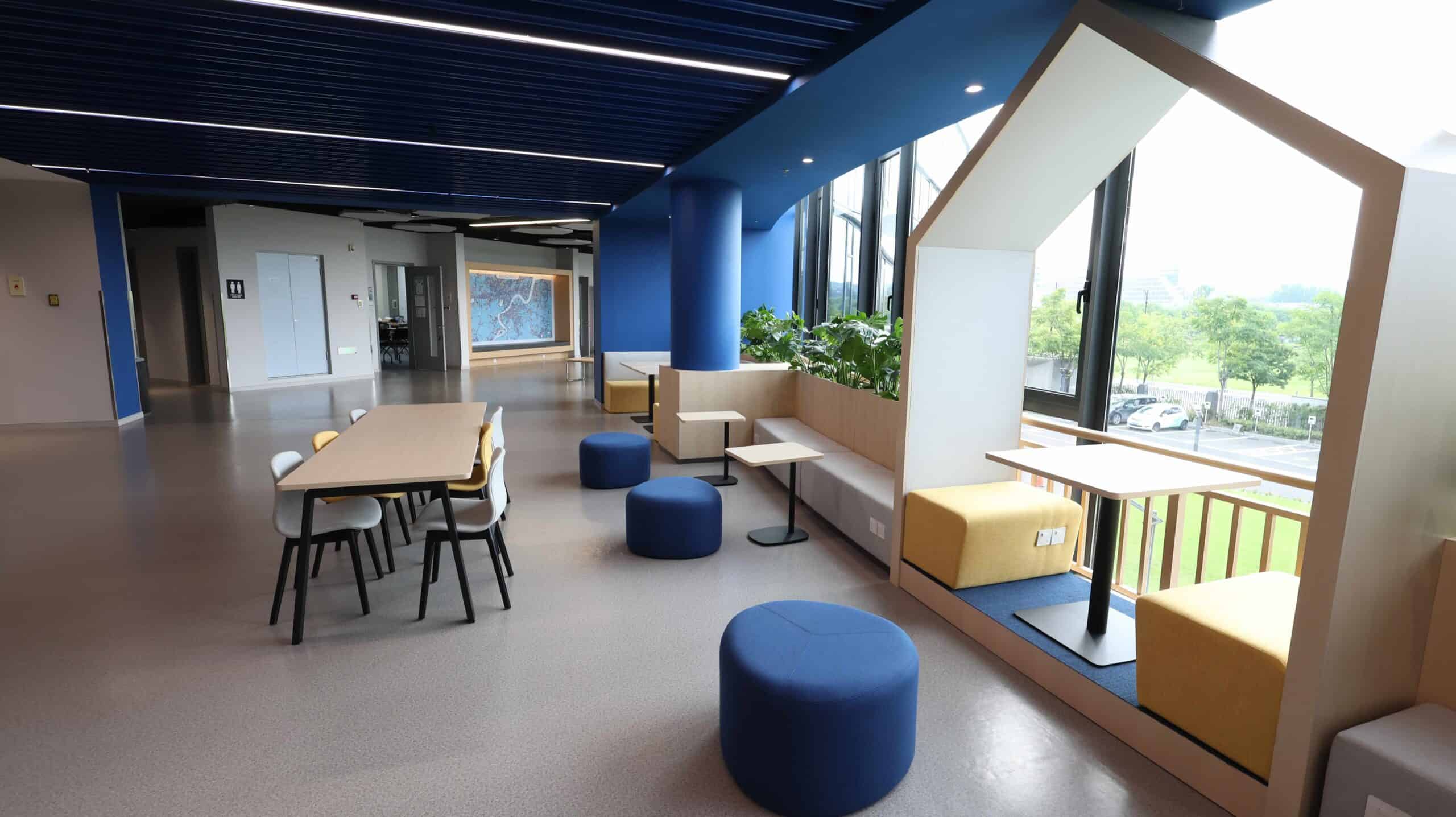 Modern school lounge with colorful seating and large windows, promoting student relaxation and social interaction.
