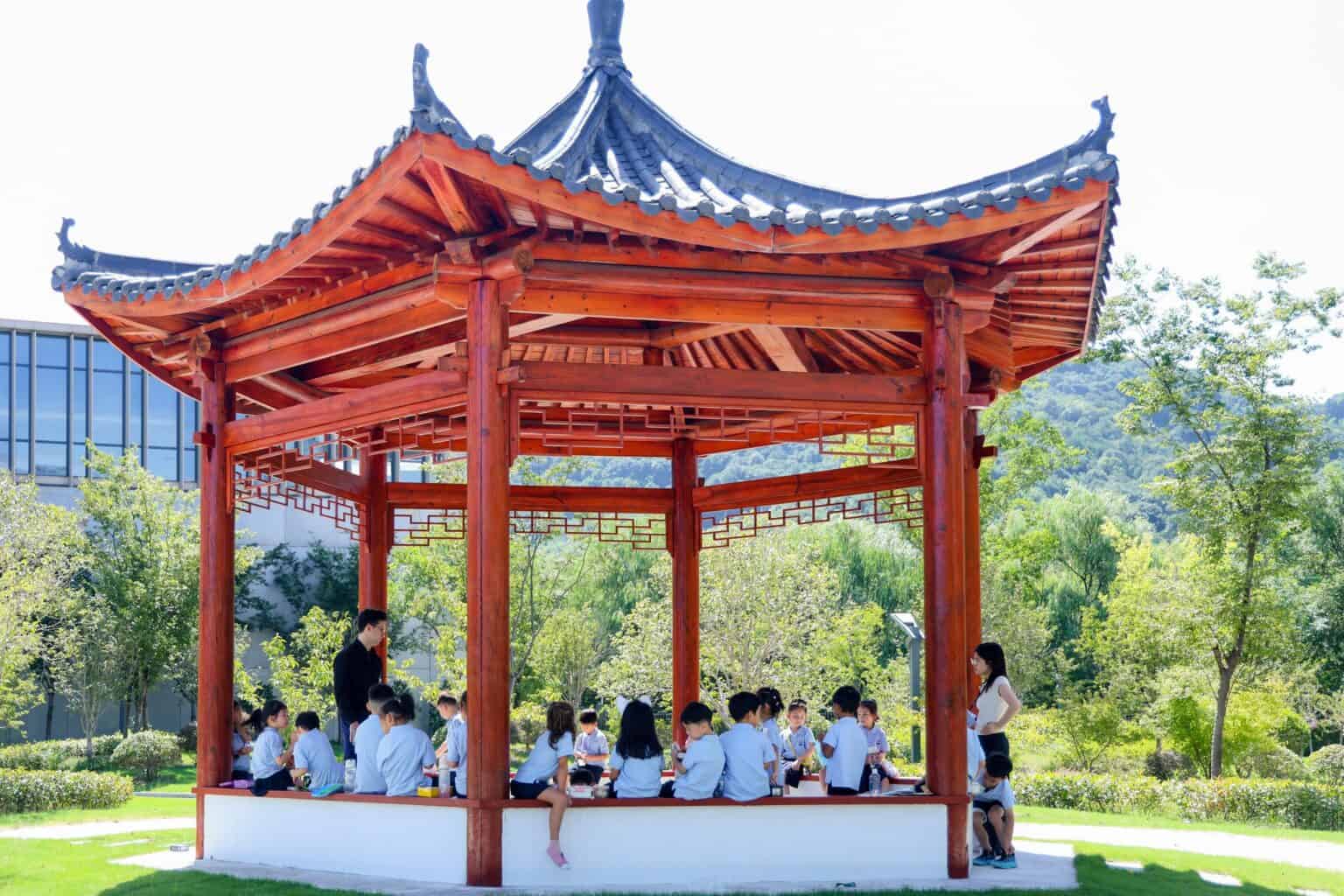 Students learning outdoors in traditional Chinese pavilion at a world school.