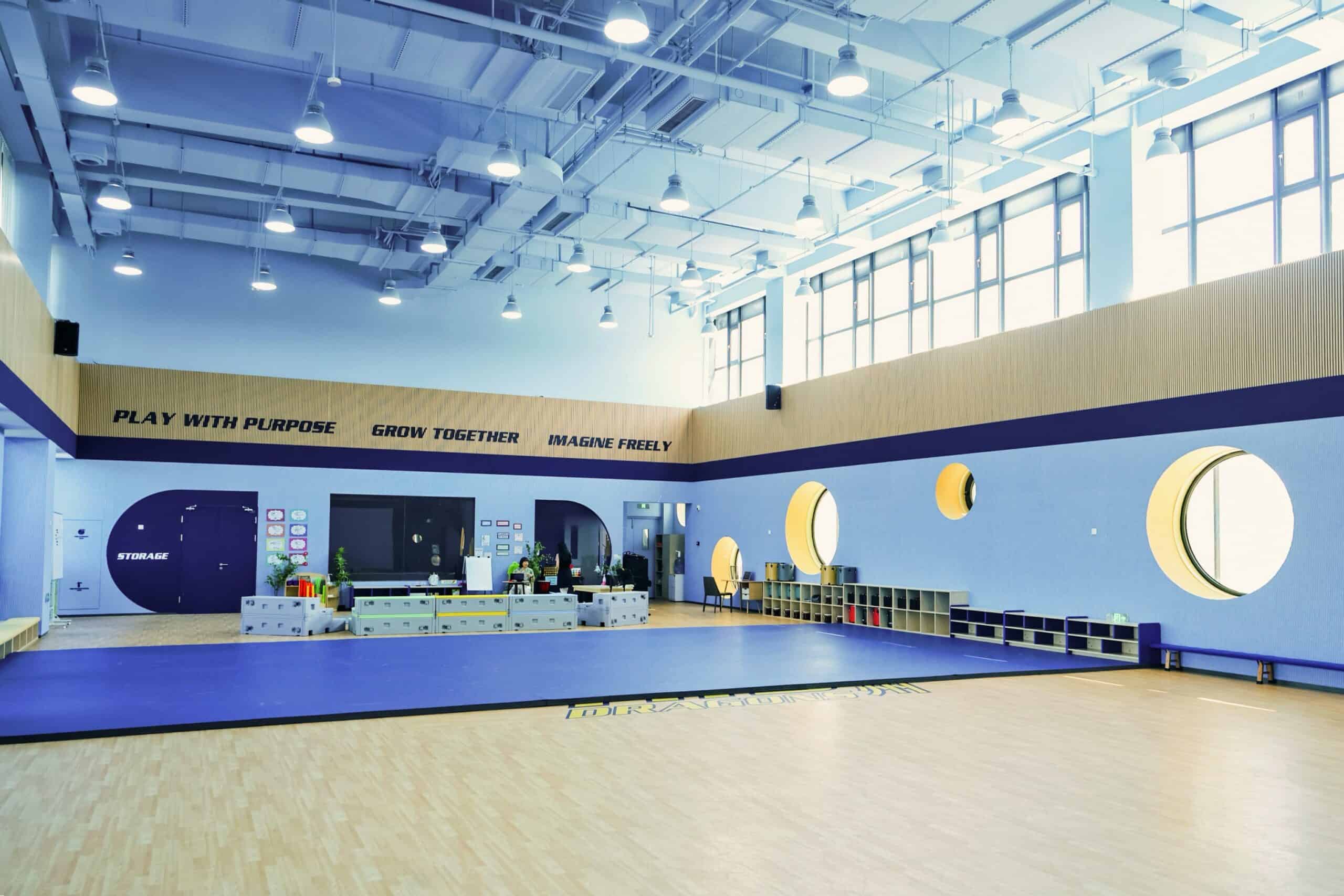 Bright modern school gymnasium with large windows, colorful decor, and motivational quotes.