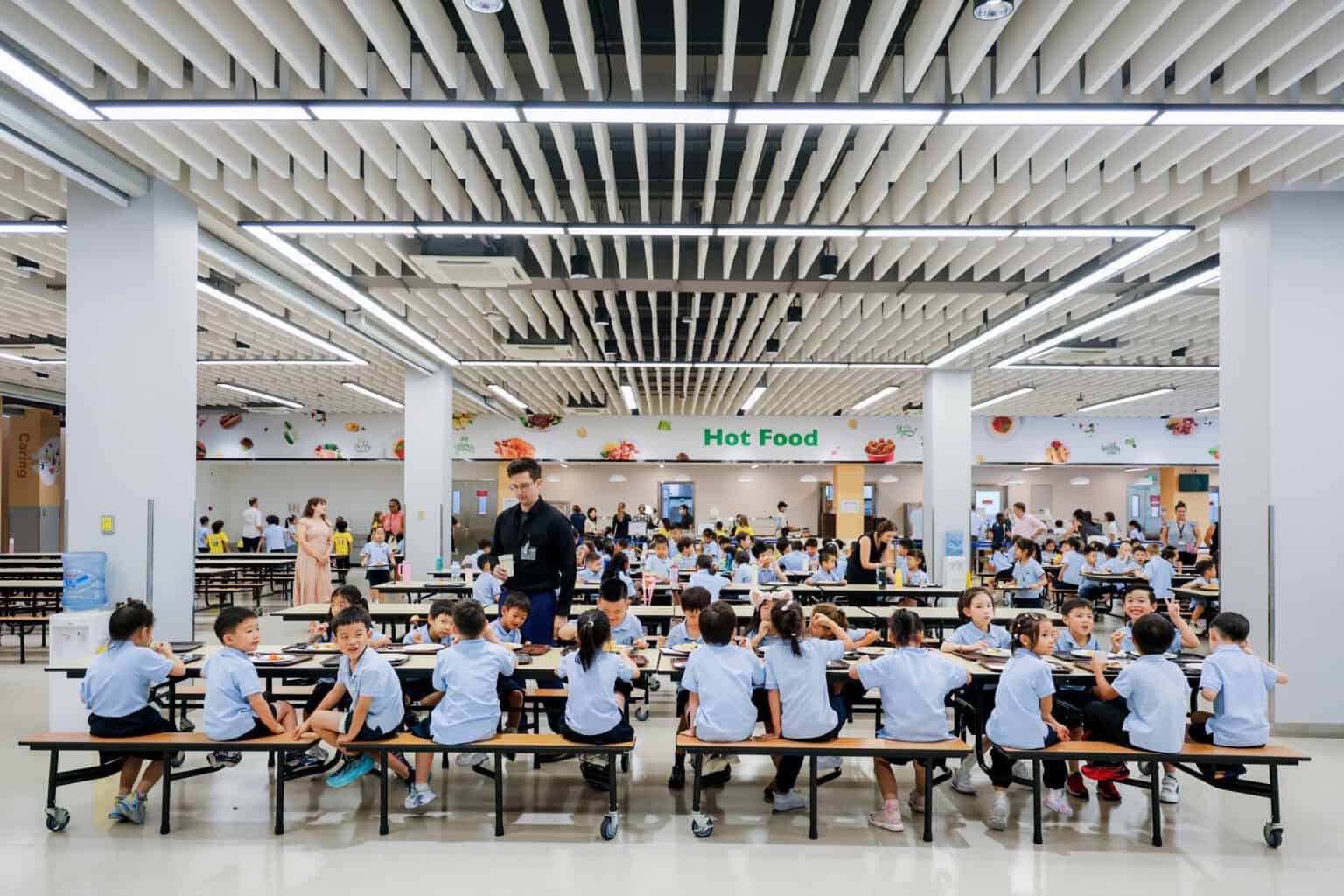 Bright school cafeteria with students, healthy hot food, and modern lighting for optimal learning environment.