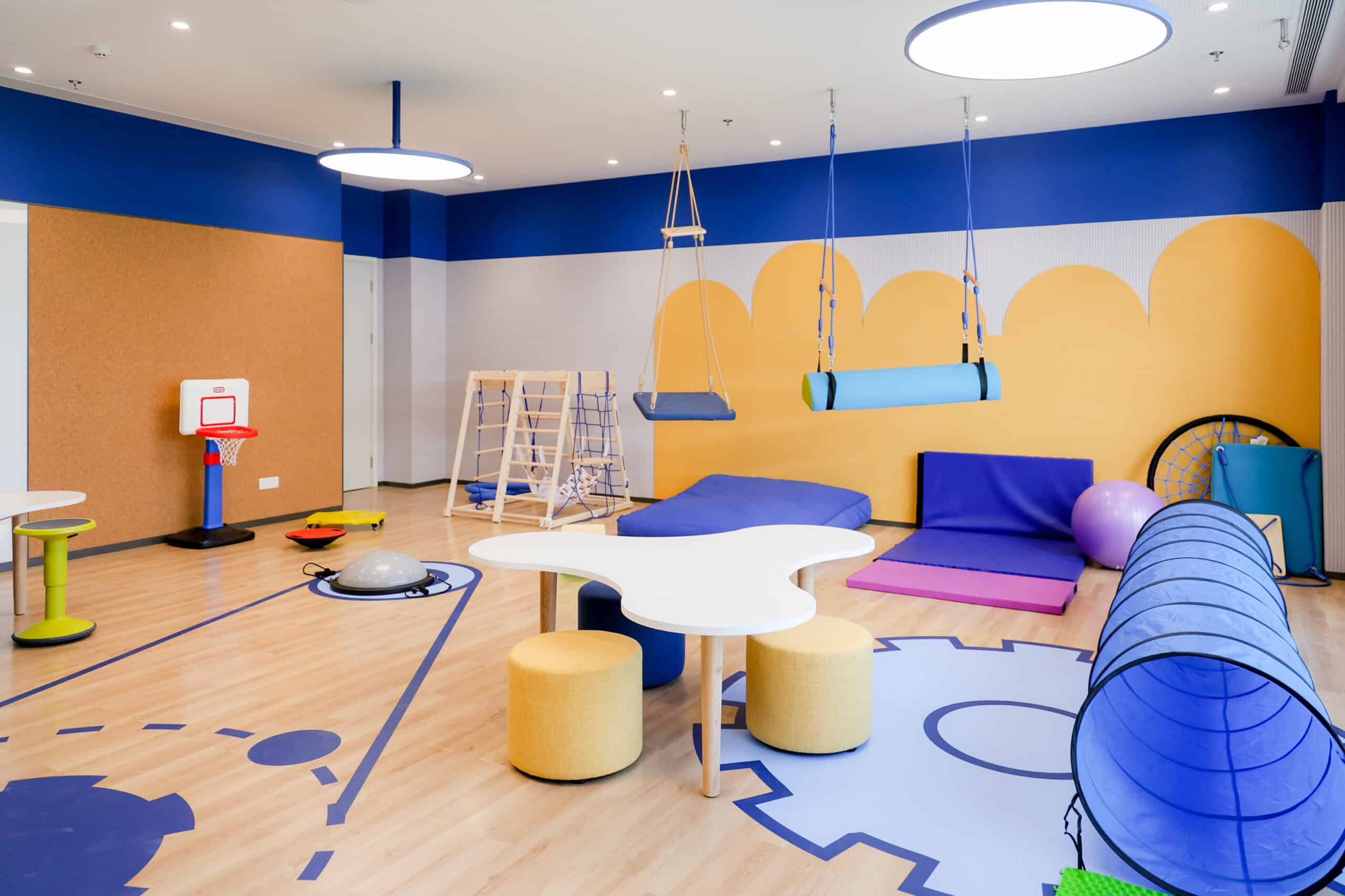 Bright indoor play area with swings, cushions, and sports equipment at a world school.