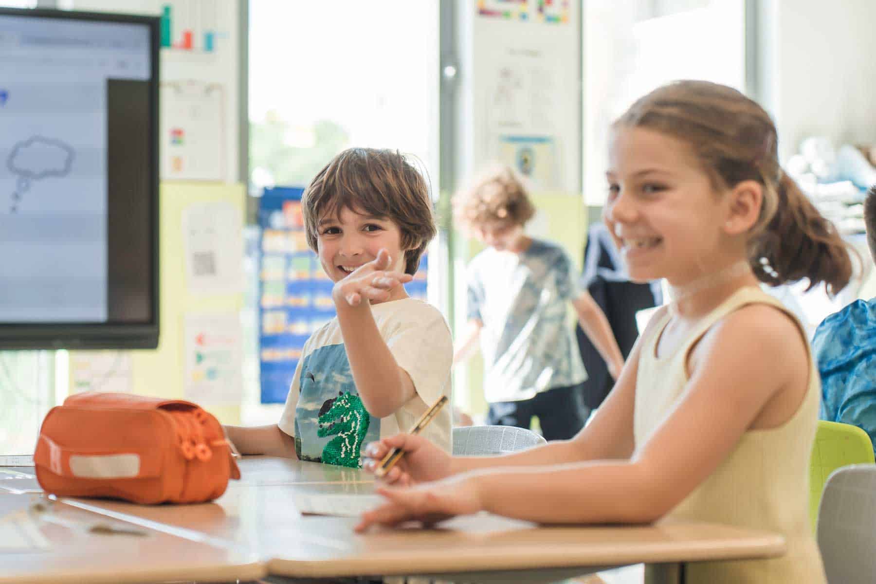 Smiling young students in a bright classroom, engaging in interactive learning at a world school.
