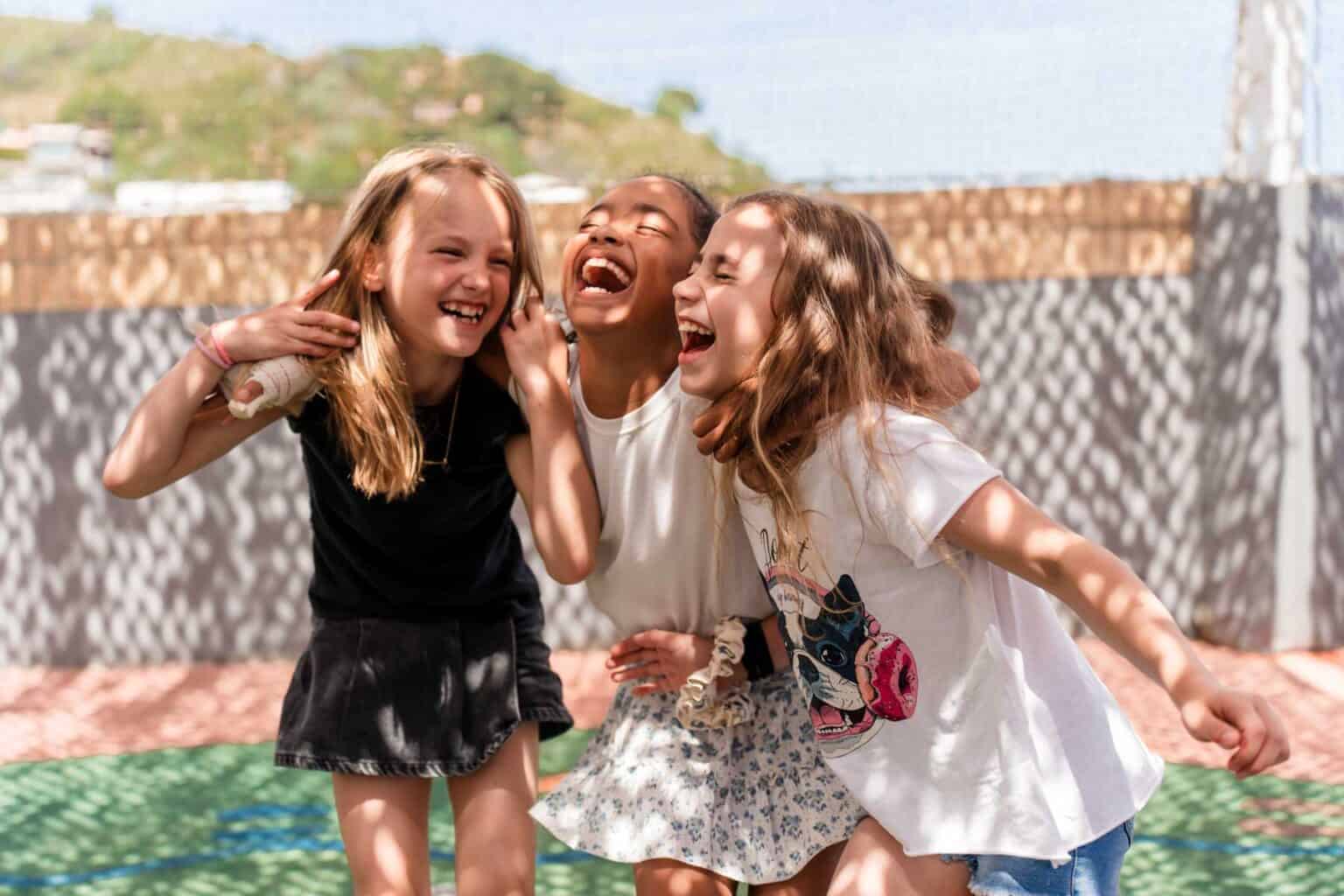 Happy children laughing and playing outdoors at a school playground, promoting joyful learning environments.