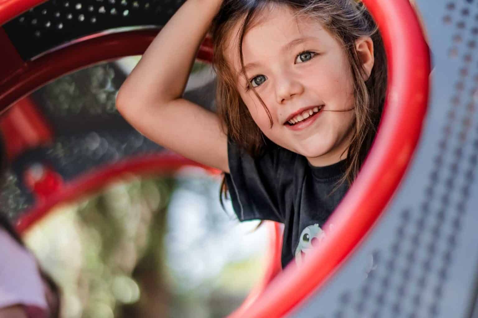 Happy young girl smiling and playing outside, enjoying childhood fun at the playground.