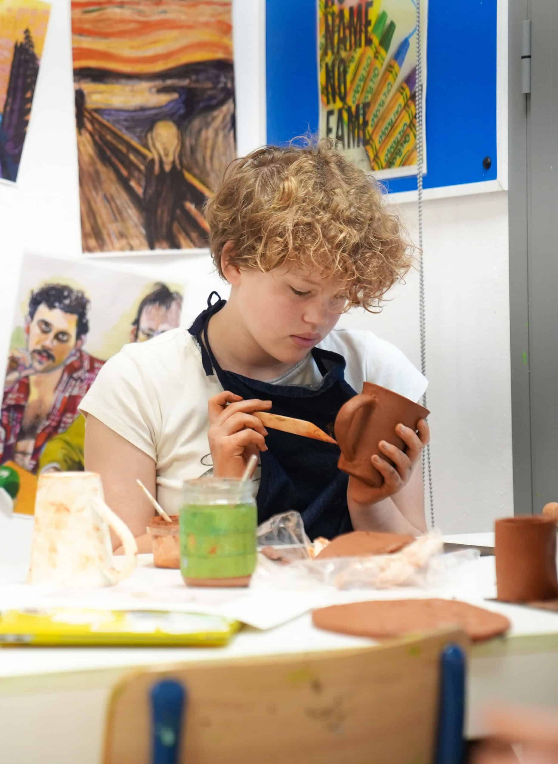 1. Young student creating pottery art in a creative classroom.