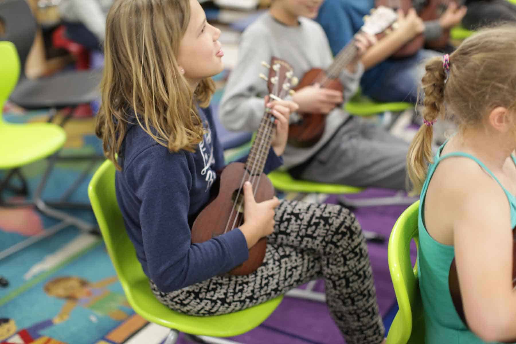 Bright young students playing ukuleles in an engaging classroom music lesson at an international school.