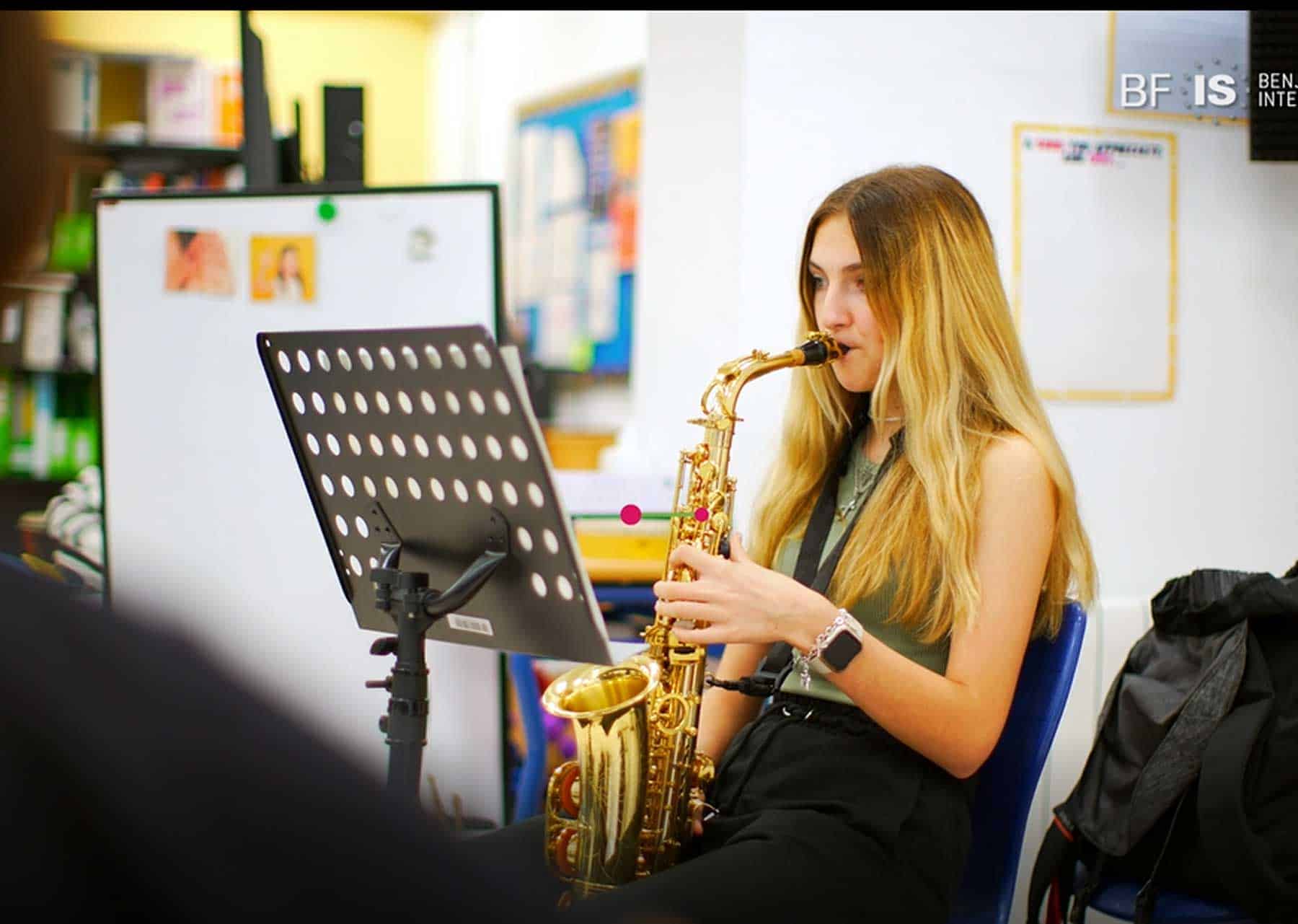 Young student playing saxophone in a classroom, promoting music education at World Schools.