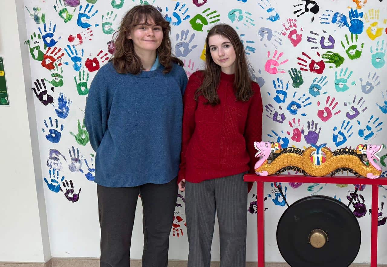 1. Diverse students standing in front of colorful handprint wall at World Schools.