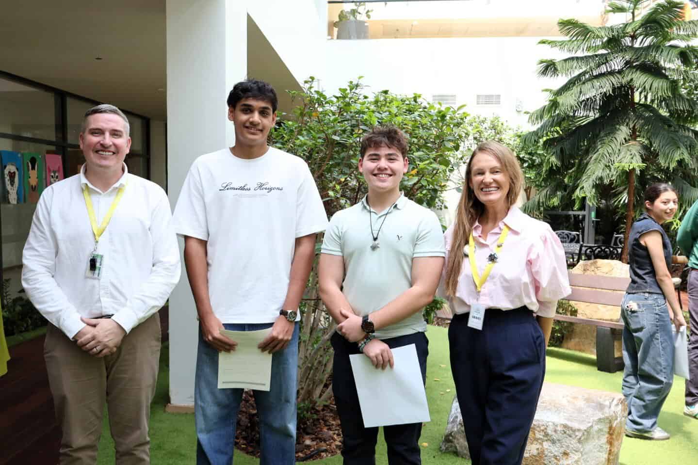 Group of students and teachers at World Schools event in a lush indoor garden.