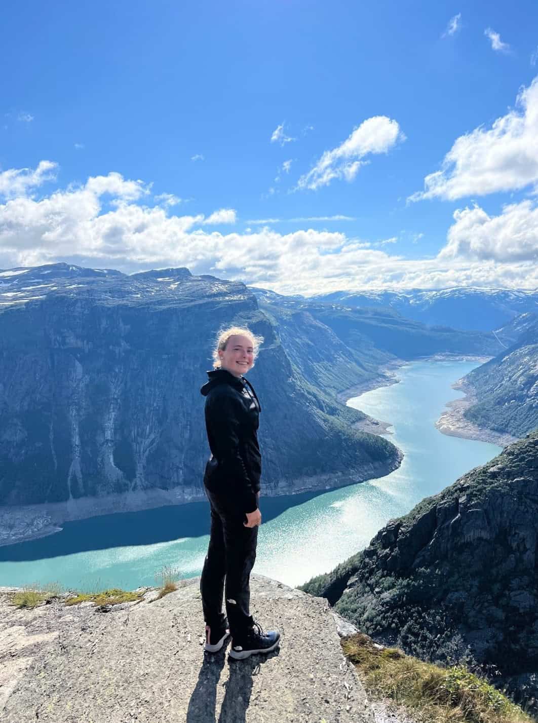 High school student enjoying scenic mountain view and fjord, enhancing outdoor education and adventure learning.