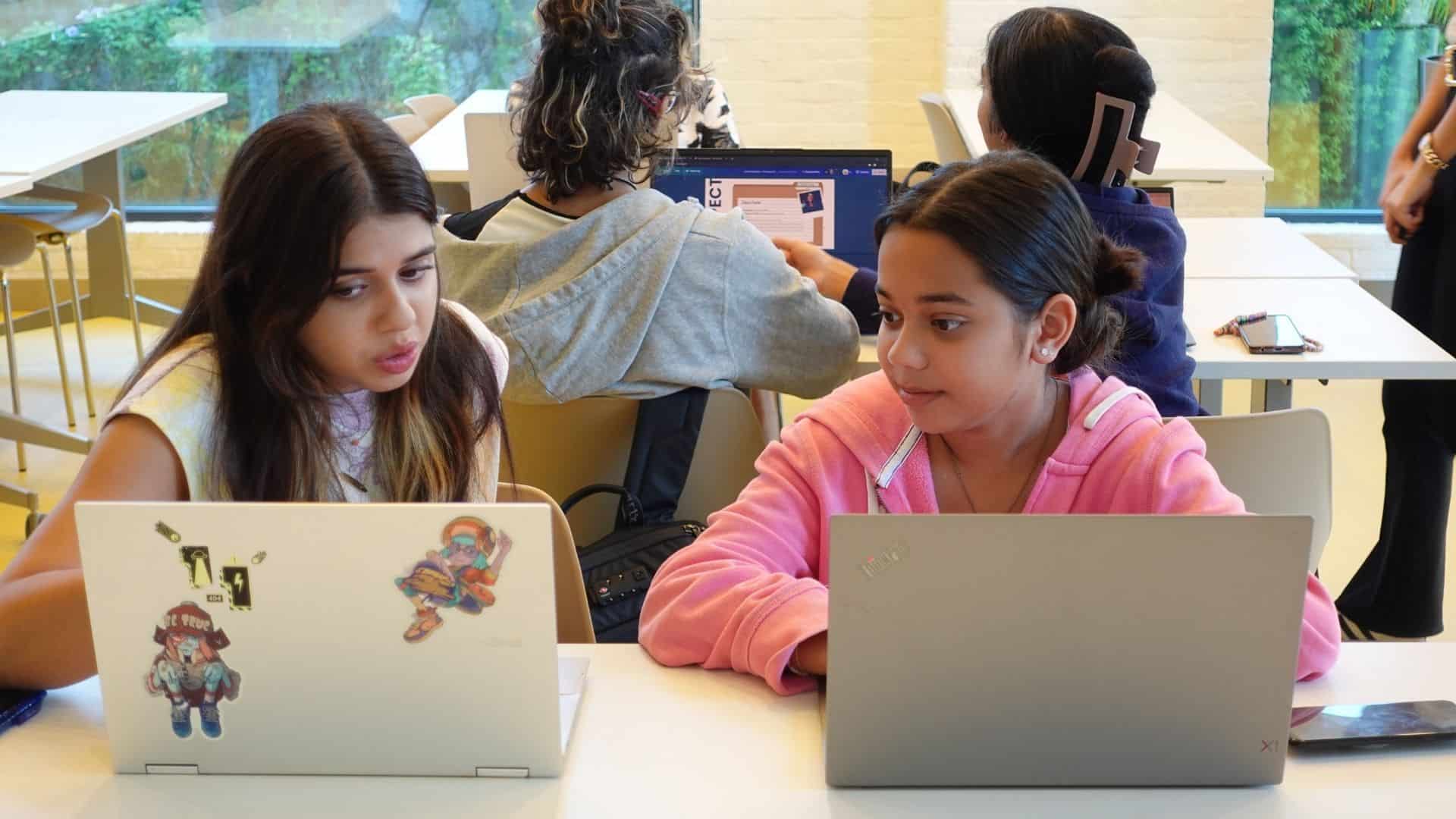 College students collaborating on laptops in a modern classroom, promoting global education and innovative learning at World Schools.