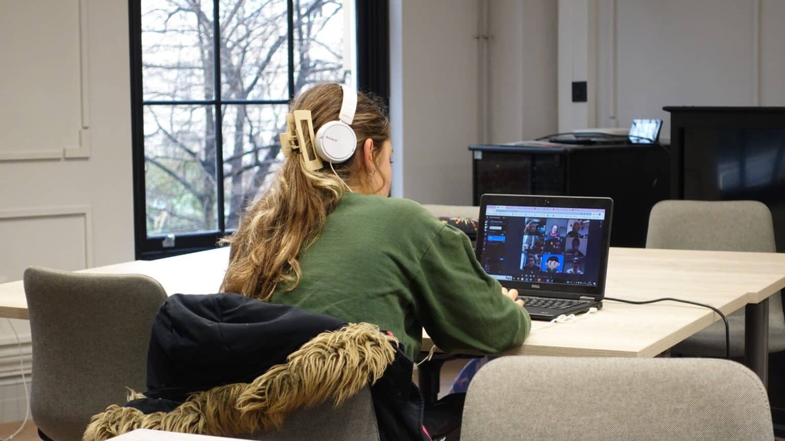 Young student participating in virtual learning at a desk with laptop and headphones.