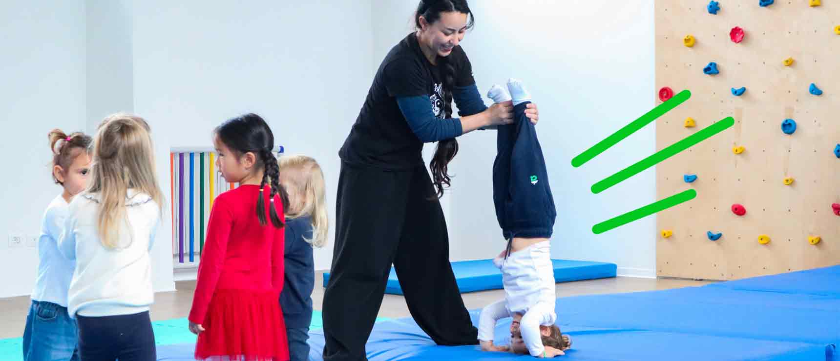 Brightly lit indoor activity with children, teacher, and climbing wall at World Schools educational facility.