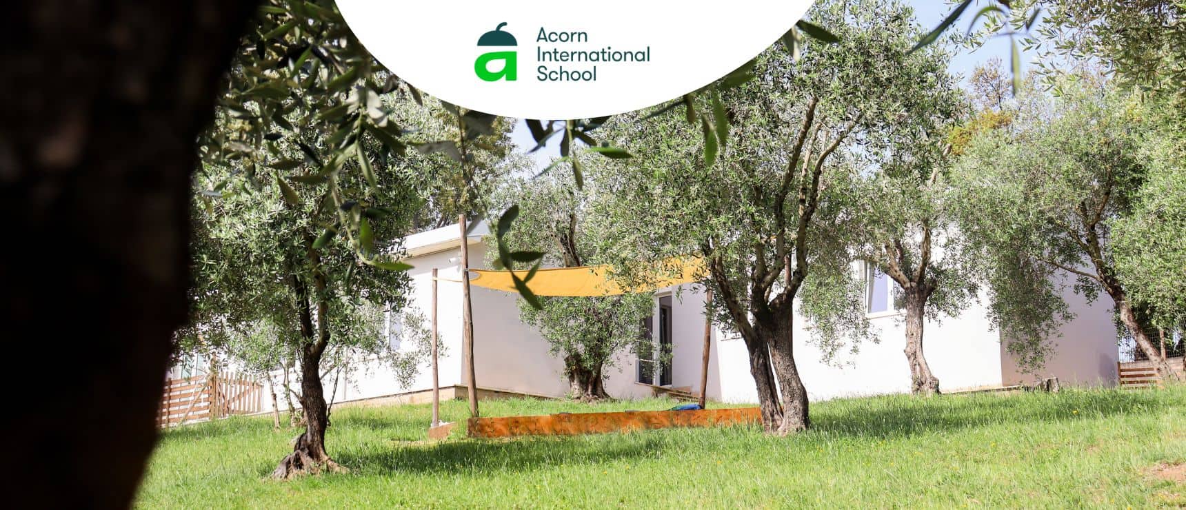Modern school campus surrounded by trees and greenery.