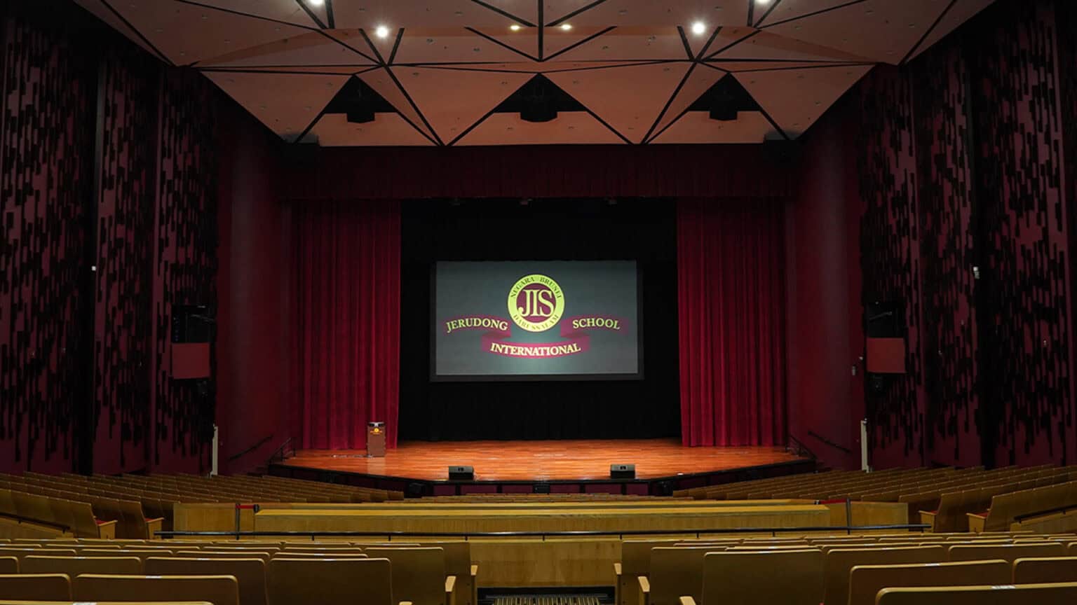Modern school auditorium with stage and seating, home to Jerudong International School events.