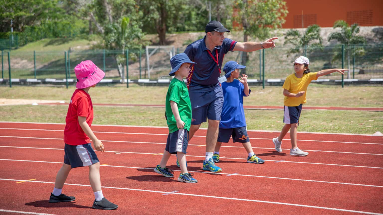 Brightly dressed children participating in outdoor track and field activity at a world school sports event.