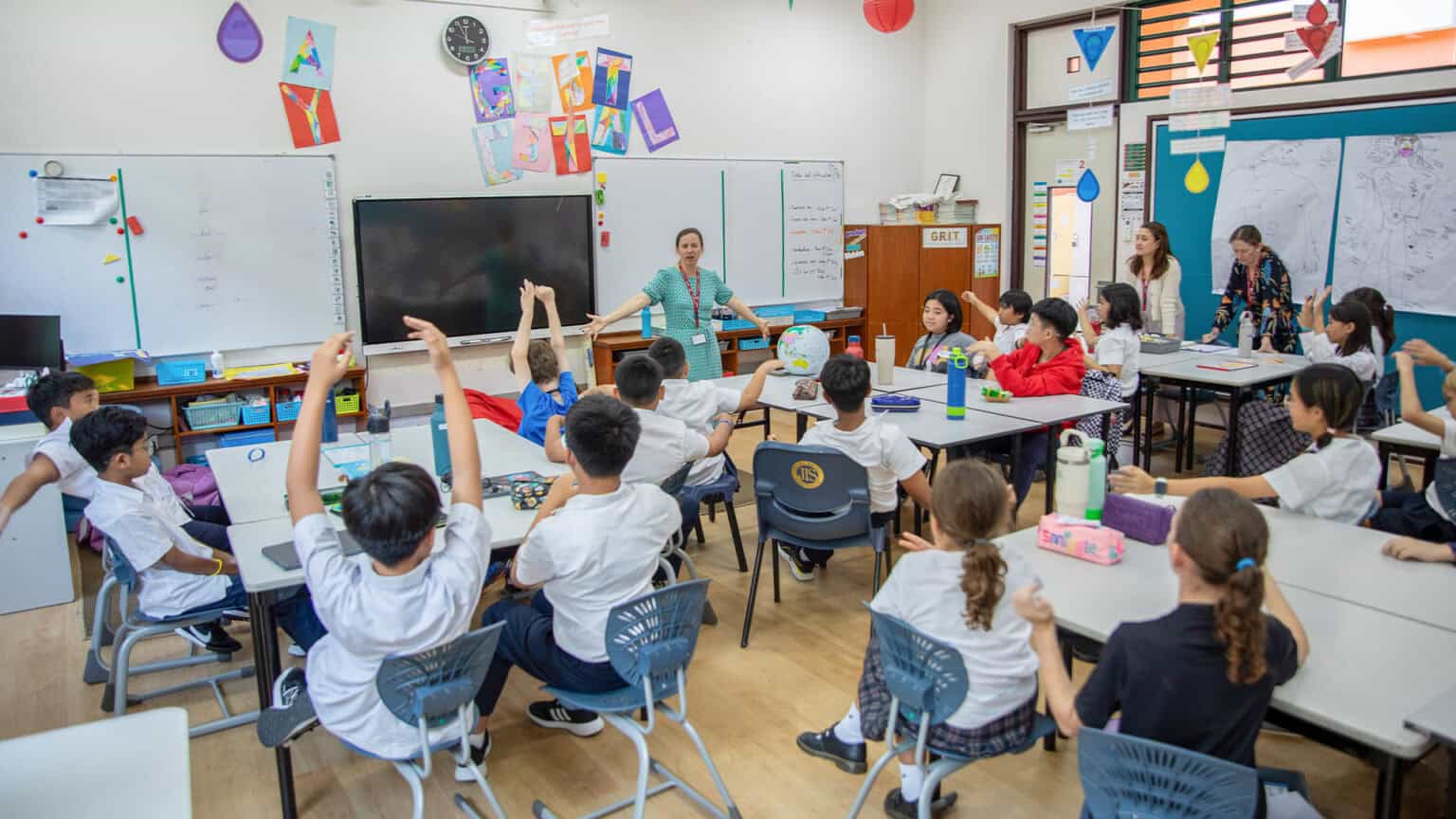 Bright elementary classroom with engaged diverse students participating in interactive lesson.